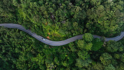 aerial view of a road in the middle of the forest , road curve construction up to mountain