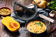 bowl of pumpkin vegetarian cream soup on dark wooden background with ingredients.
