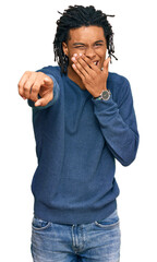 Young african american man wearing casual winter sweater laughing at you, pointing finger to the camera with hand over mouth, shame expression