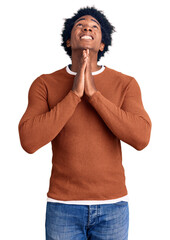 Wall Mural - Handsome african american man with afro hair wearing casual clothes begging and praying with hands together with hope expression on face very emotional and worried. begging.