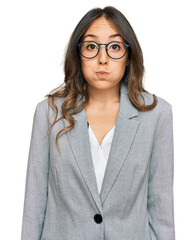 Wall Mural - Young brunette woman wearing business clothes puffing cheeks with funny face. mouth inflated with air, crazy expression.