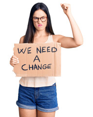 Sticker - Young beautiful caucasian woman holding we need a change banner annoyed and frustrated shouting with anger, yelling crazy with anger and hand raised