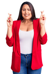 Wall Mural - Young beautiful brunette woman wearing elegant clothes gesturing finger crossed smiling with hope and eyes closed. luck and superstitious concept.