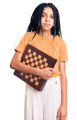 Sticker - Cute african american girl holding chess thinking attitude and sober expression looking self confident