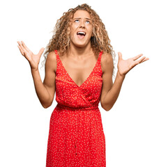 Sticker - Beautiful caucasian teenager girl wearing summer dress crazy and mad shouting and yelling with aggressive expression and arms raised. frustration concept.