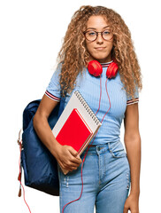 Sticker - Beautiful caucasian teenager girl holding student backpack and books thinking attitude and sober expression looking self confident