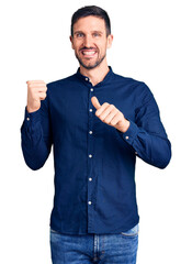 Sticker - Young handsome man wearing casual shirt pointing to the back behind with hand and thumbs up, smiling confident