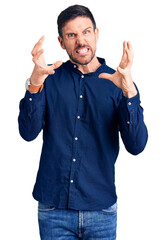 Wall Mural - Young handsome man wearing casual shirt shouting frustrated with rage, hands trying to strangle, yelling mad