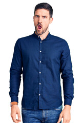 Canvas Print - Young handsome man wearing casual shirt in shock face, looking skeptical and sarcastic, surprised with open mouth