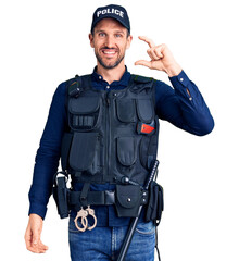 Canvas Print - Young handsome man wearing police uniform smiling and confident gesturing with hand doing small size sign with fingers looking and the camera. measure concept.