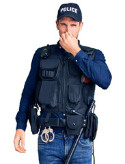 Poster - Young handsome man wearing police uniform smelling something stinky and disgusting, intolerable smell, holding breath with fingers on nose. bad smell