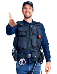 Poster - Young handsome man wearing police uniform smiling friendly offering handshake as greeting and welcoming. successful business.