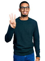 Wall Mural - Young african american man wearing casual clothes and glasses showing and pointing up with fingers number three while smiling confident and happy.