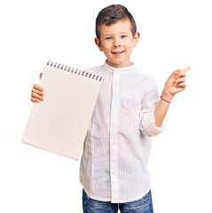 Poster - Cute blond kid holding notebook smiling happy pointing with hand and finger to the side