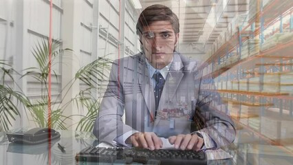 Poster - Animation of aerial view of warehouse over caucasian businessman typing on keyboard at office