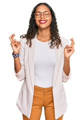 Canvas Print - Young african american girl wearing business clothes gesturing finger crossed smiling with hope and eyes closed. luck and superstitious concept.