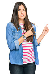 Sticker - Young brunette woman wearing casual clothes pointing aside worried and nervous with both hands, concerned and surprised expression