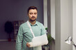 © Studio Romantic - Young man with broken arm wearing arm splint Portrait of bearded man with plaster in arm sling bandage looking at camera at home or office . Medical care, traumatology, physical injury