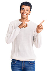 Canvas Print - Young african amercian man wearing casual clothes smiling and looking at the camera pointing with two hands and fingers to the side.