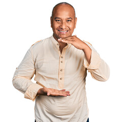 Wall Mural - Hispanic middle age man wearing boho shirt gesturing with hands showing big and large size sign, measure symbol. smiling looking at the camera. measuring concept.