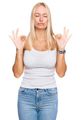 Poster - Young blonde girl wearing casual style with sleeveless shirt relaxed and smiling with eyes closed doing meditation gesture with fingers. yoga concept.