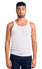 Poster - Young hispanic man wearing casual clothes puffing cheeks with funny face. mouth inflated with air, crazy expression.