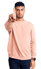 Canvas Print - Young hispanic man wearing casual clothes pointing with finger up and angry expression, showing no gesture