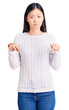 © Krakenimages.com - Young beautiful chinese woman wearing casual sweater pointing down looking sad and upset, indicating direction with fingers, unhappy and depressed.
