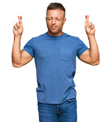 Canvas Print - Handsome muscle man wearing casual clothes gesturing finger crossed smiling with hope and eyes closed. luck and superstitious concept.