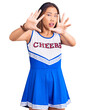 Young beautiful chinese girl wearing cheerleader uniform afraid and terrified with fear expression stop gesture with hands, shouting in shock. panic concept.
