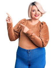 Wall Mural - Young blonde plus size woman wearing casual sweater smiling and looking at the camera pointing with two hands and fingers to the side.