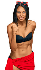 Wall Mural - Young african american woman wearing bikini angry and mad raising fist frustrated and furious while shouting with anger. rage and aggressive concept.