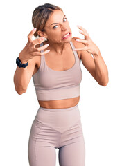 Wall Mural - Beautiful caucasian woman wearing sportswear shouting frustrated with rage, hands trying to strangle, yelling mad