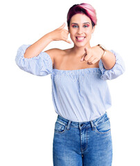 Canvas Print - Young beautiful woman with pink hair wearing casual clothes smiling doing talking on the telephone gesture and pointing to you. call me.