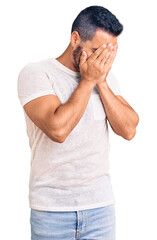 Wall Mural - Young hispanic man wearing casual clothes with sad expression covering face with hands while crying. depression concept.