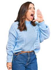 Canvas Print - Young brunette woman wearing casual winter sweater shouting and screaming loud to side with hand on mouth. communication concept.