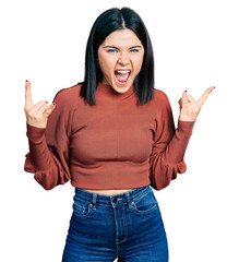 Poster - Young brunette woman with blue eyes wearing elegant sweater shouting with crazy expression doing rock symbol with hands up. music star. heavy concept.