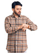 © Krakenimages.com - Young hispanic man wearing casual clothes checking the time on wrist watch, relaxed and confident