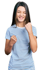 Wall Mural - Young brunette girl with long hair wearing casual striped t shirt celebrating surprised and amazed for success with arms raised and eyes closed