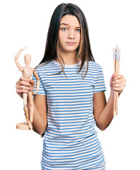 Sticker - Young brunette girl with long hair holding small wooden manikin and pencils skeptic and nervous, frowning upset because of problem. negative person.