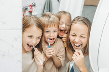 Mother And Children Brush Their Teeth In The Bathroom.