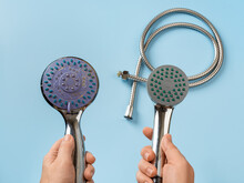 Woman hands hold old and new shower heads. Compare old shower head with limescale and new clean one in female hands over blue background. Domestic plumbing work, bath and washing concept.