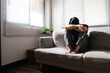 © Pichsakul - Man with mental health problem sitting on couch to resting head on his arms with depressed emotion