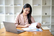 © Wasana - Asian businesswoman sitting and working check documents analyze market reports. Review and compare report data.