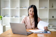 © Wasana - Asian businesswoman sitting and working check documents analyze market reports. Review and compare report data.