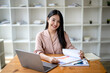 © Wasana - Asian businesswoman sitting and working check documents analyze market reports. Review and compare report data.