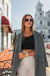 © alones - Beautiful urban stylish business girl with vintage sunglasses in fashionable clothes with a blazer walks in the city on a sunny spring day. Pretty chic lady
