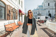 © alones - Urban fashion beautiful woman with sunglasses in stylish spring outfit with blazer walks on the street near a vintage buildings