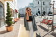 © alones - Fashionable beautiful woman in fashion clothes with a bag and blazer walks in the city and adjusts her stylish sunglasses on a sunny spring day