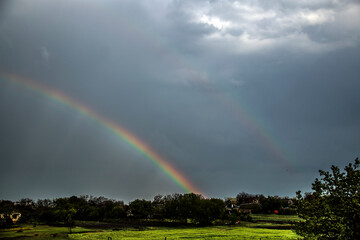 Wall Mural - Double rainbow in the sky during rain in a cloudy sky over a village	
